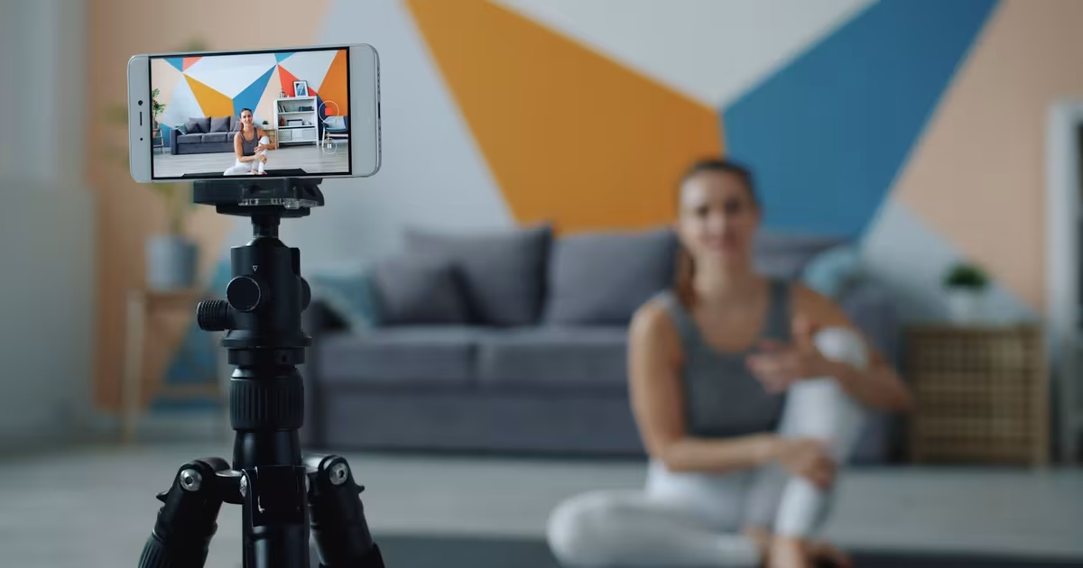 A person filming a workout on a smartphone in a bright gym, illustrating fitness creator content on TikTok.