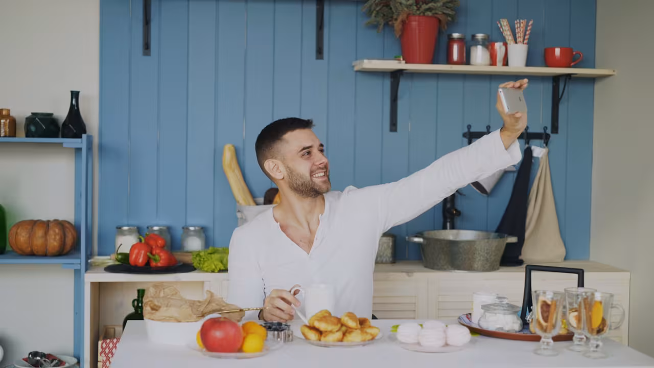 Local food creator at a casual restaurant table discreetly filming a vertical video of a plated taco dish on a phone, warm ambient interior light.