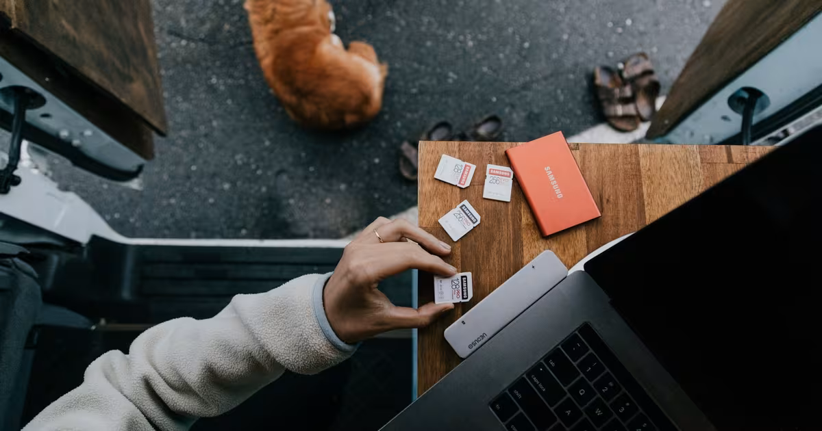 Over-the-shoulder view of a marketer composing an influencer outreach email on a laptop, with a small product package sitting beside the keyboard to suggest product seeding.