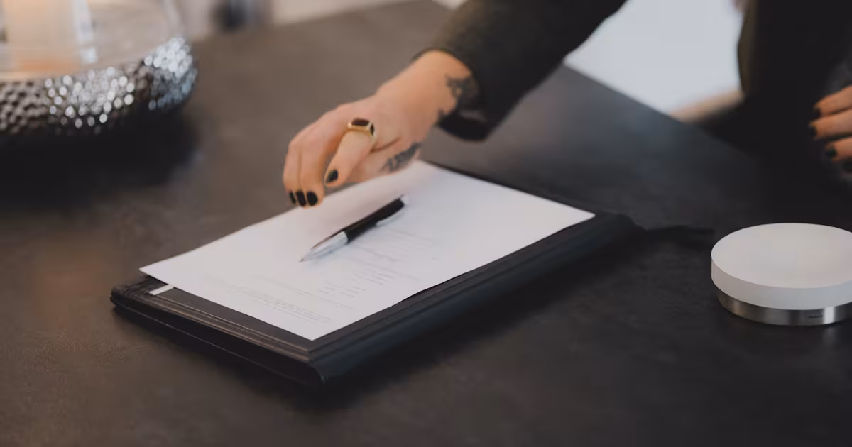 Hand signing a digital micro-influencer contract on a tablet with a stylus on a clean desk in soft daylight.