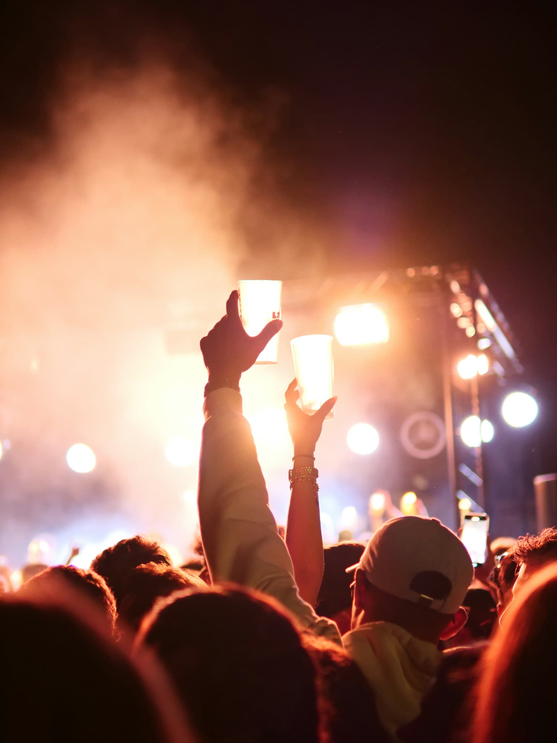 A nighttime concert crowd with raised hands and bright stage lights
